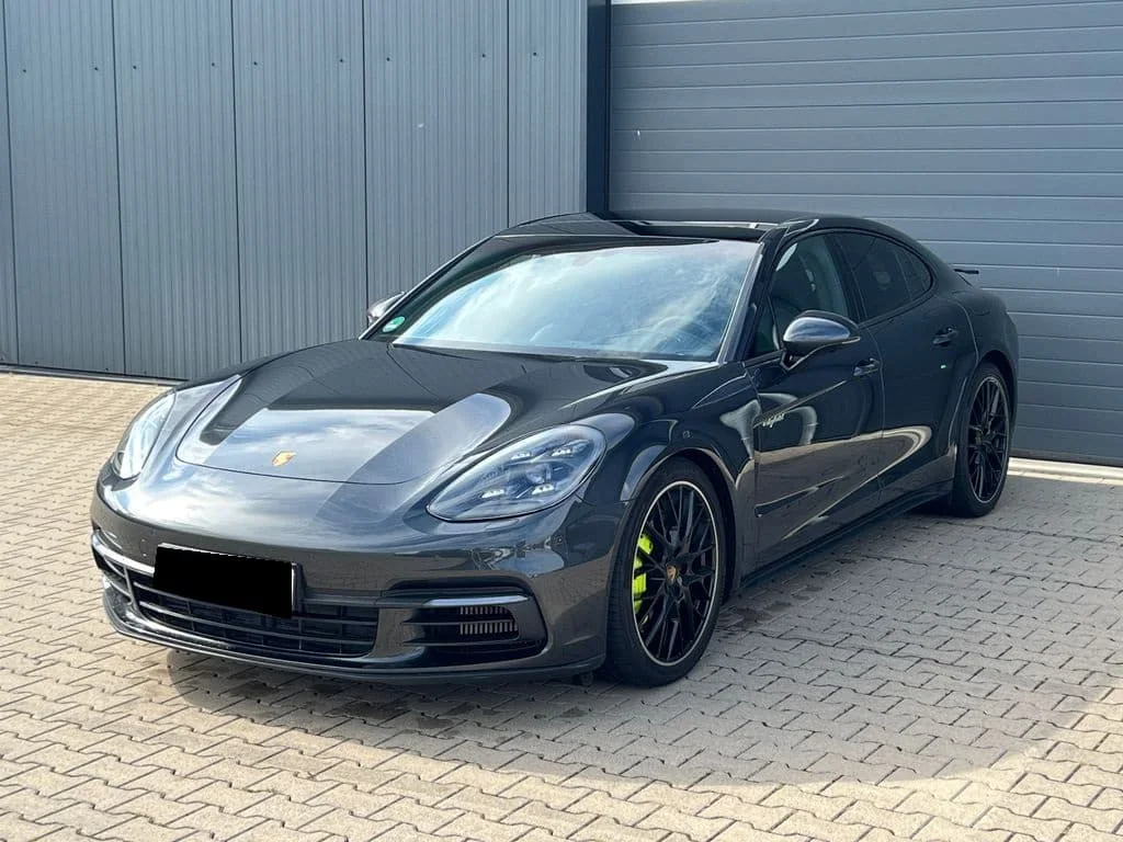Porsche grise stationnée devant un bâtiment aux portes métalliques.