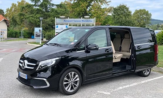 Van Mercedes noir, porte coulissante ouverte, devant le panneau de l’aéroport Cannes-Mandelieu.